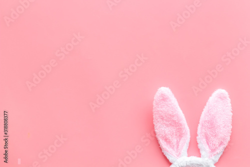 Easter bunny concept. Toy rabbit's ears on pink background top-down copy space