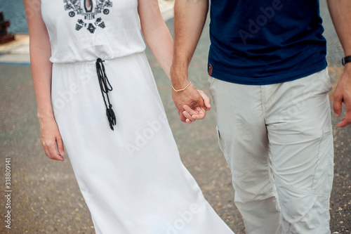 a pair of lovers without faces hold hands and walk on open air, a girl dressed in a white sundress with embroidery in a rustic style of boho