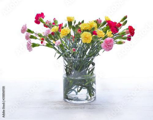 pretty bouquet of colorful flowers - carnation-  in a glass jar on white back...