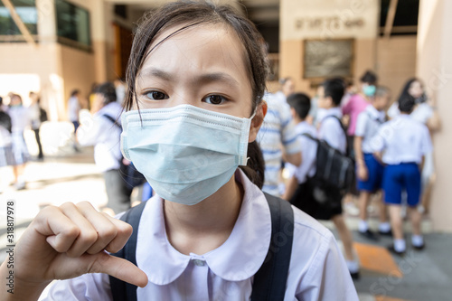 Asian child girl student thumbs down wearing medical face mask in school,epidemic,spread of germ,Coronavirus,MERS-CoV,air contamination,Wuhan coronavirus 2019-nCoV, concept of Corona virus quarantine
