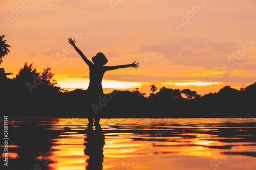 Woman silhouette over sunset sky with reflection in water