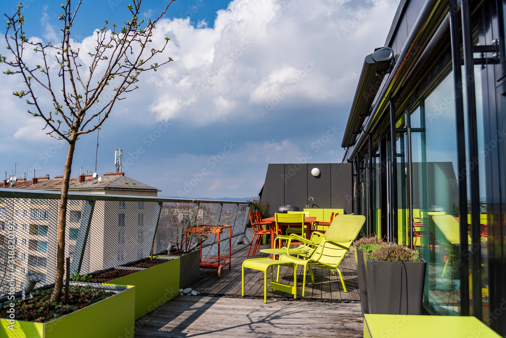 Green and terracotta  all-season weatherproof furniture for outdoor use on a rooftop terrace .