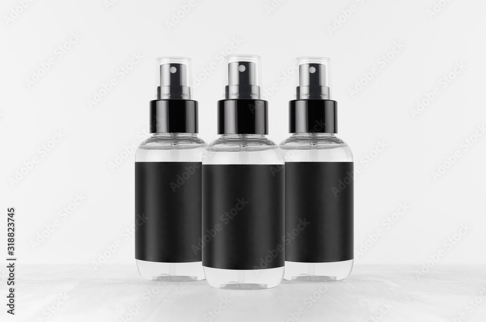 Transparent spray bottles for cosmetics product with black blank label on white wood board, mock up for branding, advertising, presentation, design. Transparent spray bottles for cosmetics product with black blank label on white wood board, mock up for branding, advertising, presentation, design.