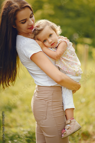 Family sitting in a summer park. Mother in a white t-shirt. Cute little girl