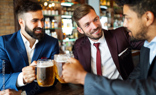 Handsome businessmen are drinking beer, talking and smiling while resting at the pub