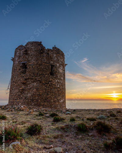 Cala Domestica Beach, spanish tower at sunset in long exposure and flare effect, Buggerru, Sardinia