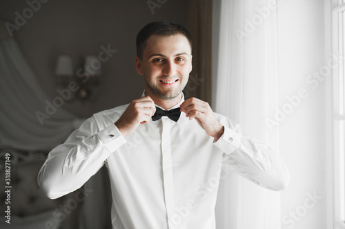 Grooms morning preparation. Handsome man getting dressed and preparing for the wedding photo