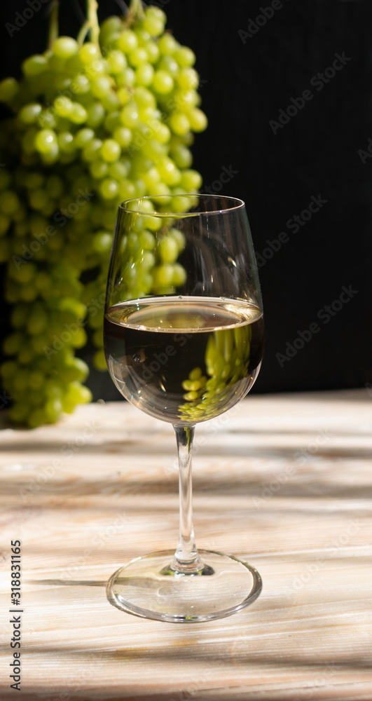 White Wine Glass on Ripe Green Grapes Background in Sunny Day