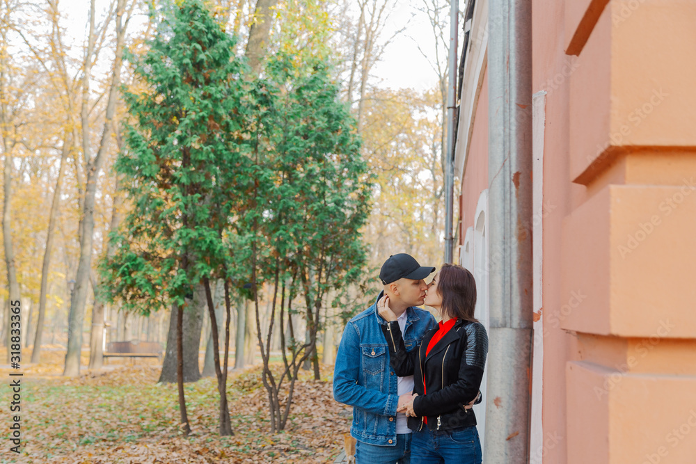 Happy lovers in the park near the wall. Autumn weather. Happy lovers in the park near the wall. Autumn weather.