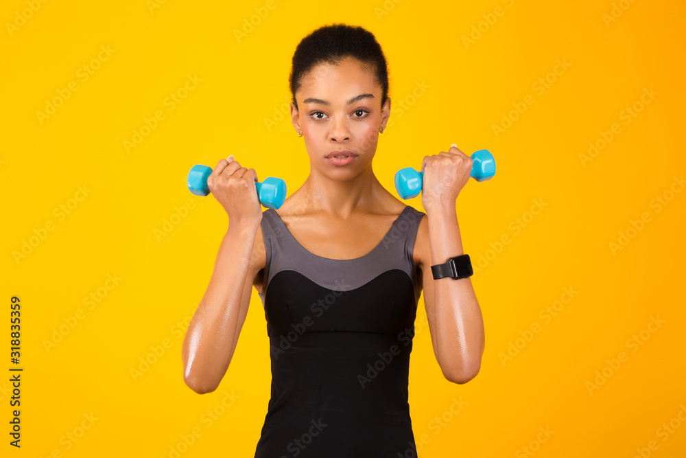 Black Girl Doing Dumbbell Bicep Curls Pumping Muscles, Yellow Background Black Girl Doing Dumbbell Bicep Curls Pumping Muscles, Yellow Background