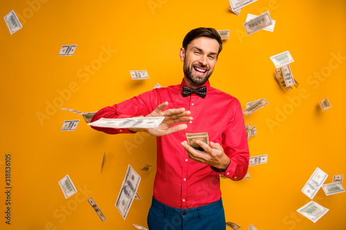 Photo of crazy funny guy hold fan of money bucks waste jackpot throw away banknotes money falling wear trendy red shirt bow tie clothes isolated yellow color background photo