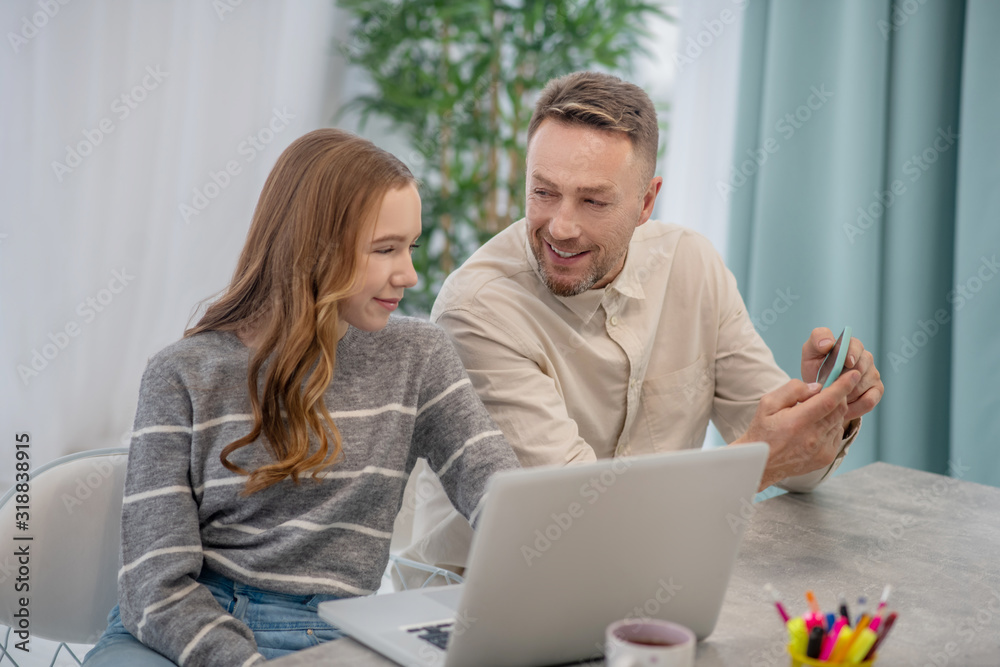 Bearded father showing pictures to his pretty daughter Bearded father showing pictures to his pretty daughter