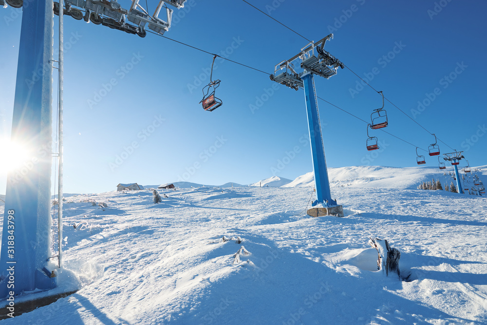 Ski lift with seats going over the mountain and paths from skies and snowboards. Beautiful winter landscape. Ski lift with seats going over the mountain and paths from skies and snowboards. Beautiful winter landscape.