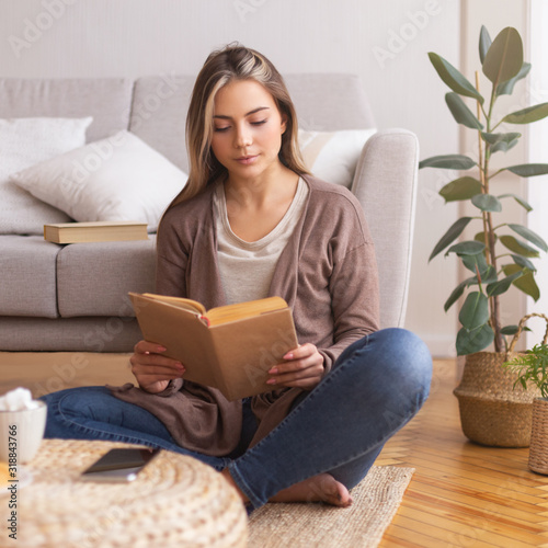 Slika na platnu Beautiful young woman reading book on floor