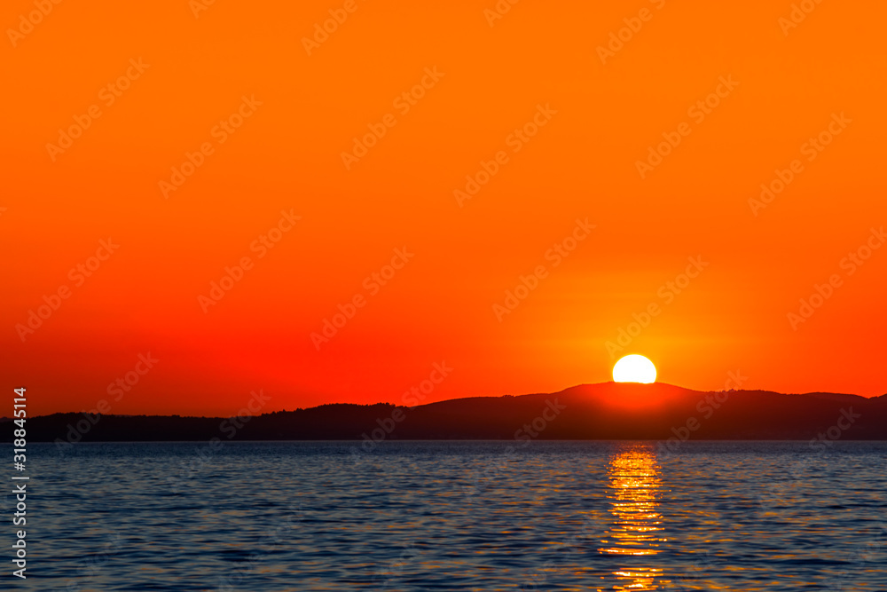 Beautiful orange sunset over the sea with sun reflection in the water, scenic view, Zadar, Dalmatia, Croatia