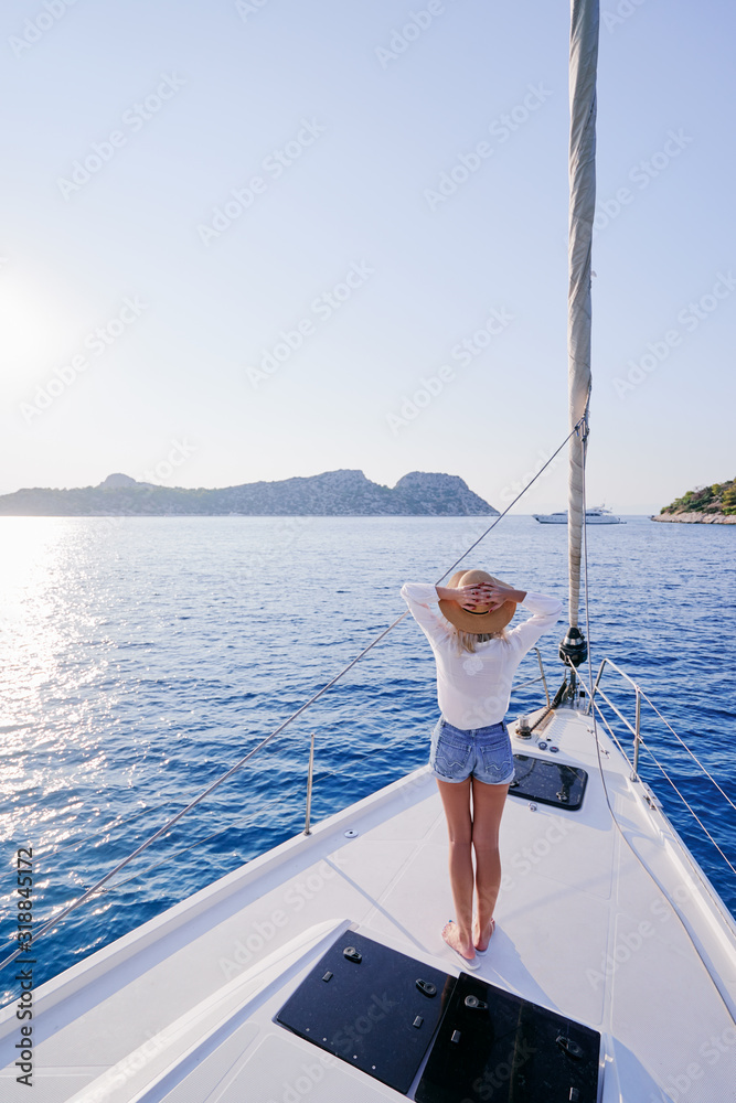 Luxury travel on the yacht. Young happy woman on boat deck sailing the sea. Yachting in Greece.