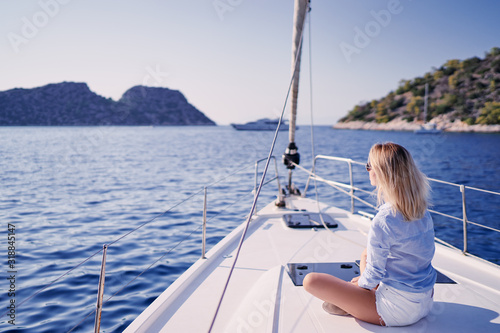 Luxury travel on the yacht. Young happy woman on boat deck sailing the sea. Yachting in Greece.