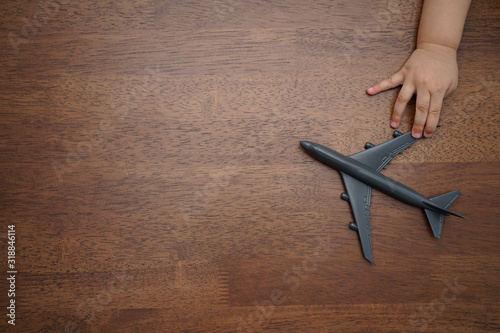 Travel concept Flat lay design with airplane with child hand on wooden background with copy space.