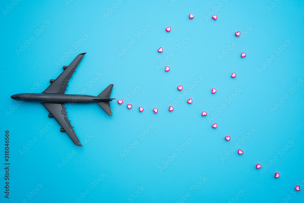 Fototapeta Travel concept Flat lay design with airplane and heart shape beads on blue background with copy space.