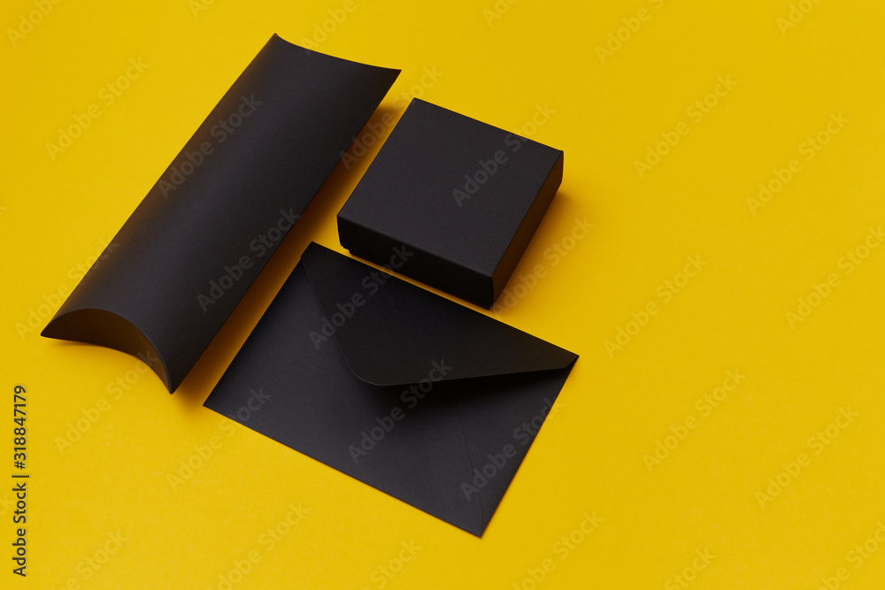 Obraz premium Mock up of two black paper present boxes and an envelope on the yellow background. Presentation template