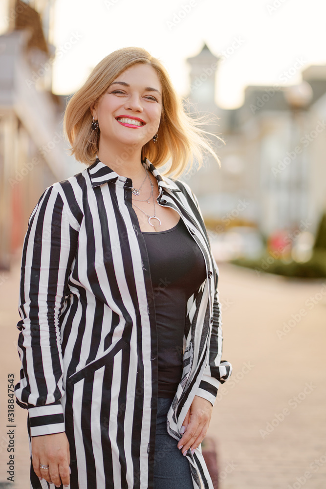 Outdoor portrait of happy young woman walking by city street.