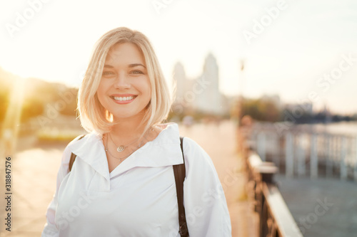 Outdoor portrait of happy young woman on city promenade.