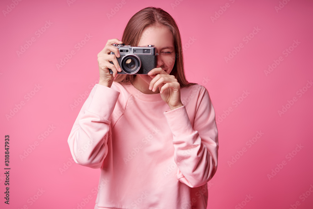 Traveler and photographer. Studio portrait of pretty young girl holding photocamera. Pink blackground. - obrazy, fototapety, plakaty 