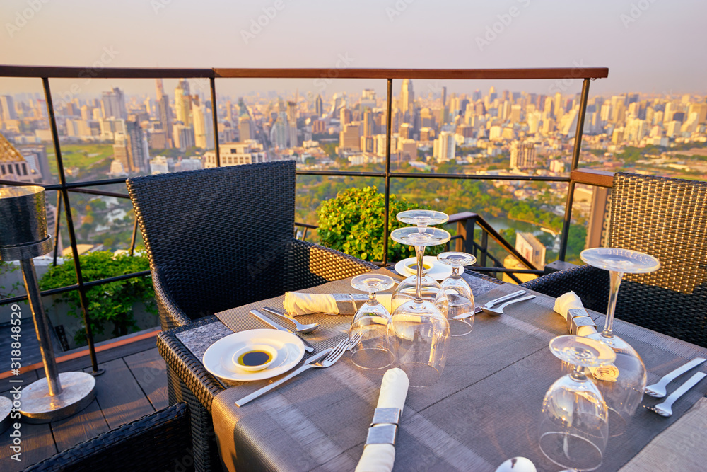 Table setting on roof top restaurant with megapolis view, Bangkok Thailand.