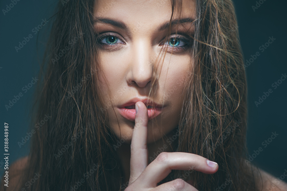 fashion model with beautiful eyes holding finger on her lips fashion model with beautiful eyes holding finger on her lips
