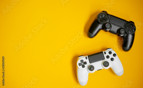 Computer game competition. Gaming concept. White and black joysticks on yellow background. © luengo_ua