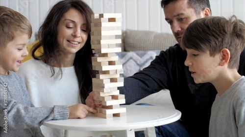 Slow motion of wooden tower is crumbling while family playing game together photo