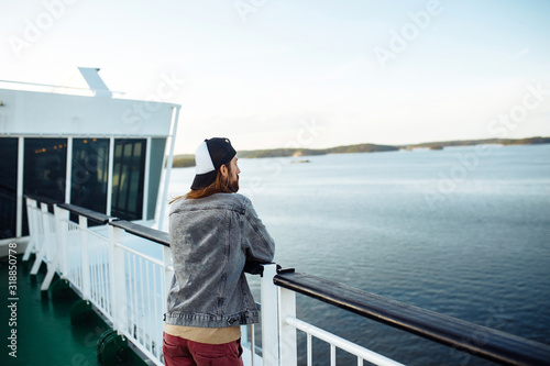 Fotografia Guy enjoys a ferry ride or ship, sailing to the island tourist destination on summer vacation in sunny day