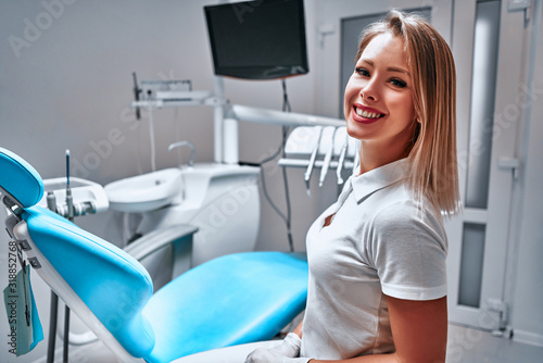 Happy young female dentist with tools over medical office background