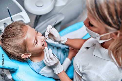 Close up view of a cute little kid doing teeth surgery by a pediatric dentist.