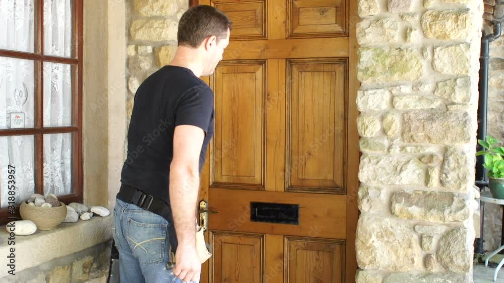 Plumber / Tradesman knocks on the front door of a house. A woman opens the house door and lets him in Plumber / Tradesman knocks on the front door of a house. A woman opens the house door and lets him in
