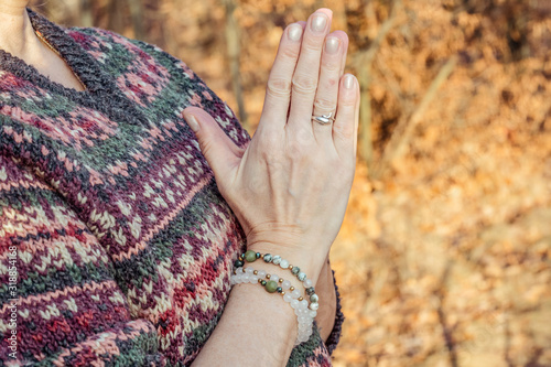 Detal of woman doing namaste hand mudra pose in the forest photo