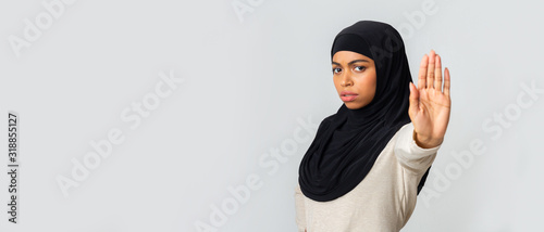 Frightened Afro Muslim Woman In Hijab Rejecting Something With Open Palm photo