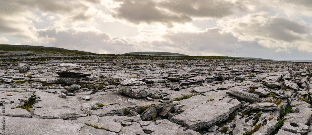 Panorama image of Burren landscape, county Clare, Ireland, Rough stone terrain, Cloudy dramatic sky.