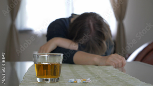 Drunk or sick woman. Acohol and drugs abuse. Woman defocused. Focus on a glass.