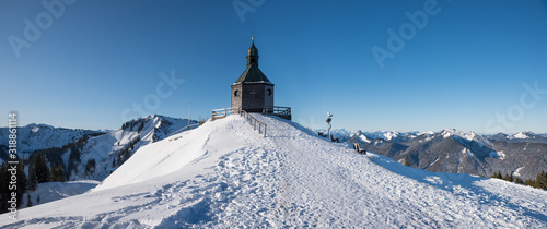 beautiful chapel in winter landscape, popular tourist destination with view to bavarian alps