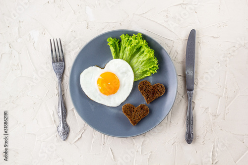 Valentines day breakfast with heart shaped fried eggs served on grey plate