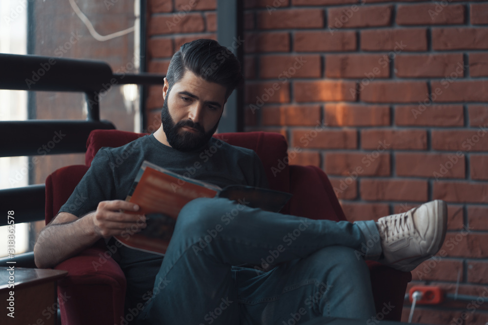 Portrait handsome bearded man wearing casual clothing, sitting in red chair modern loft studio Portrait handsome bearded man wearing casual clothing, sitting in red chair modern loft studio