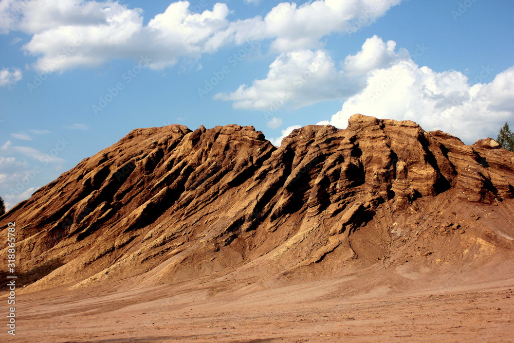 Fototapeta premium The waste heaps landscape similar to canyon after coal heaps are extracted. Consequences of opencast coal mining. Terricone against a background of blue sky with white clouds
