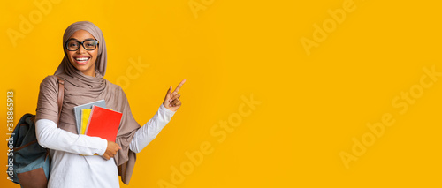 Fotografia Portrait of black muslim female student in hijab pointing at copy space