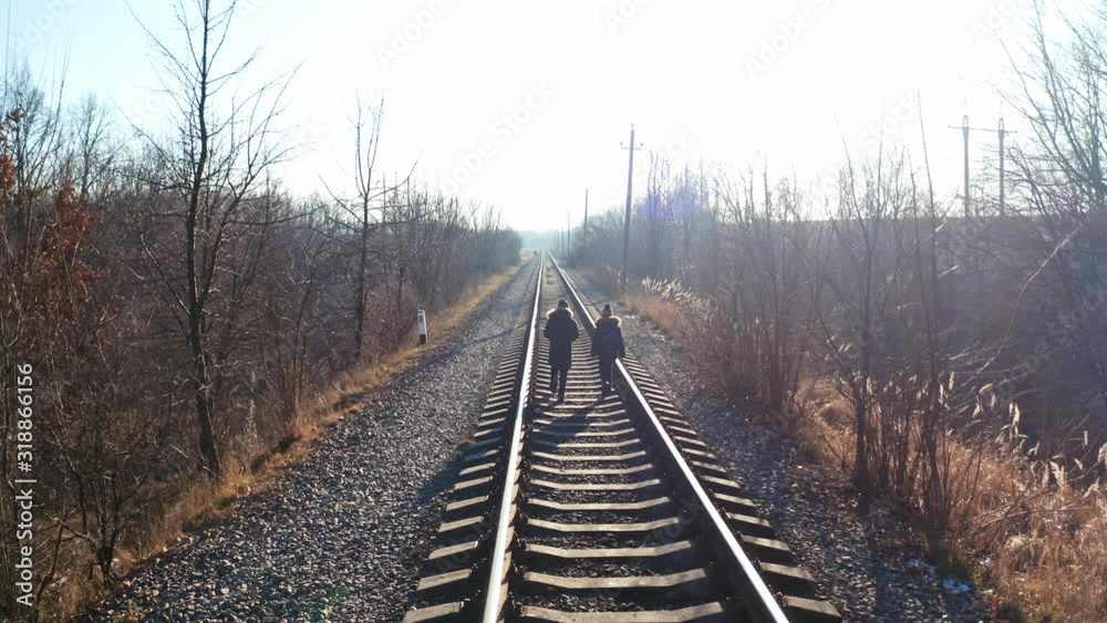 People walking on railway in forest. Traveler people walking along the railroad tracks People walking on railway in forest. Traveler people walking along the railroad tracks