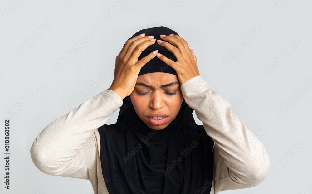 Depressed afro muslim woman holding head in hands, regret about something