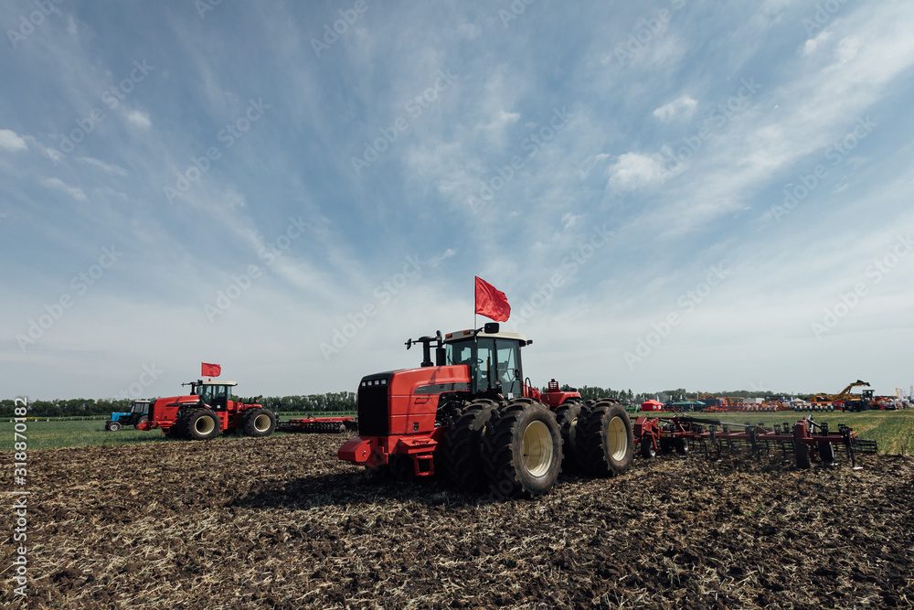 red tractor with big wheels in the field against the blue sky red tractor with big wheels in the field against the blue sky