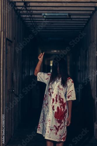 horror scence of women hold knife by hands with blood. Ghost women wear white dress stain blood at abandoned house