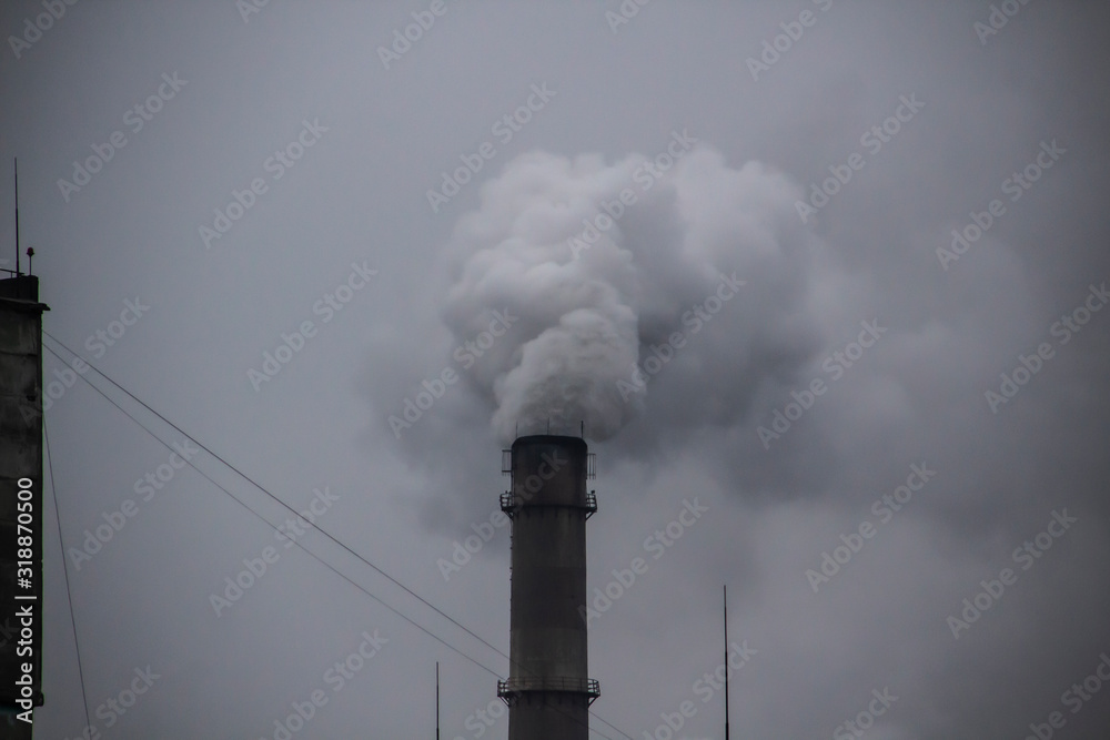 Industrial Smoke Pipe against grey sky. Industrial chimney fume mix in clouds. Smoke air emissions from pipe on a grey sky Industrial Smoke Pipe against grey sky. Industrial chimney fume mix in clouds. Smoke air emissions from pipe on a grey sky