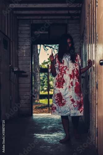 horror scence of women hold knife by hands with blood. Ghost women wear white dress stain blood at abandoned house